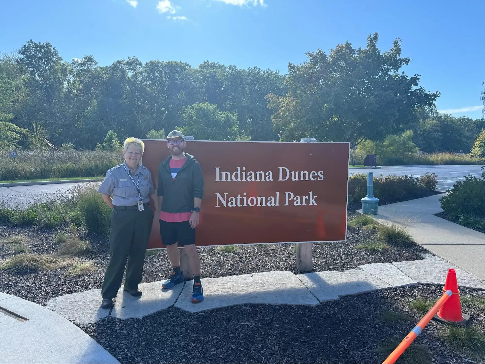 Two people standing in front of the Indiana Dunes National Park sign
