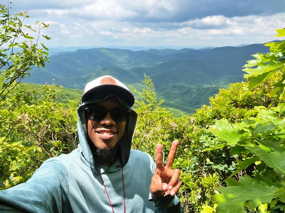 Justin Tucker making a peace sign over a green valley