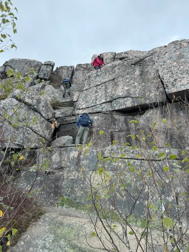 a cliff face with hikers climbing up the rocks
