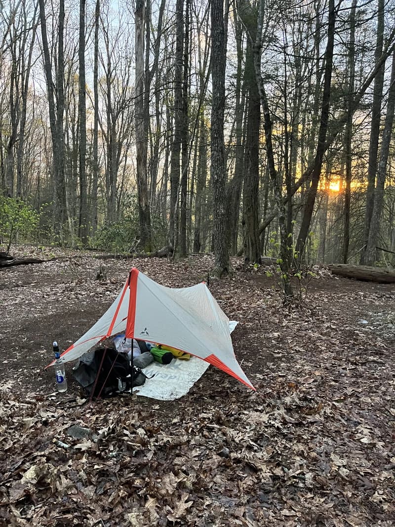 a tarp over a sleeping bag on a bed of fallen leaves